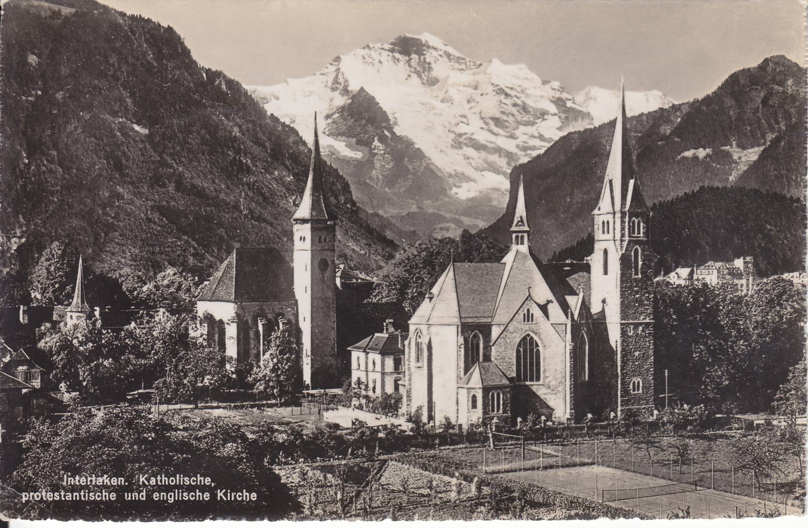 Two churches side by side at Interlaken, an old church with a square tower and a large neo-Gothic church, with the Jungfrau behind