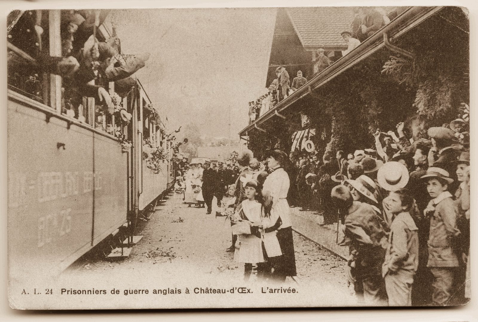 Crowds line the platform at Château-d'Œx station in 1916 as a train of British internees arrives, soldiers leaning from every window and two children in white standing at the front